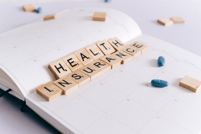 קוביות עץ עם הכיתוב Health Insurance על יומן פתוח